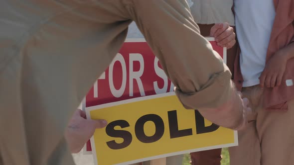 Unrecognizable Man Putting Sold on For Sale Sign