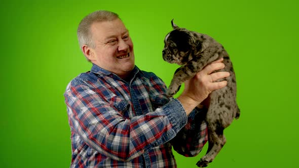 Mature Adult Caucasian Man Stroking Puppy of French Bulldog Holding in His Arms