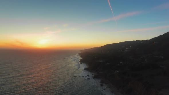 Drone footage of bright sunrise over the ocean shore at El Matador Beach, Malibu, Califronia, USA 