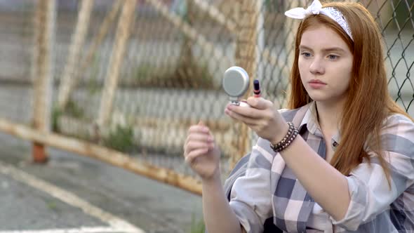 Pretty Teenage Girl Applying Lip Gloss Outdoor