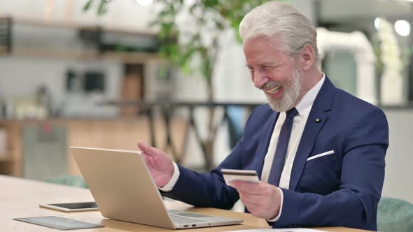 Successful Old Businessman Making Online Payment on Laptop