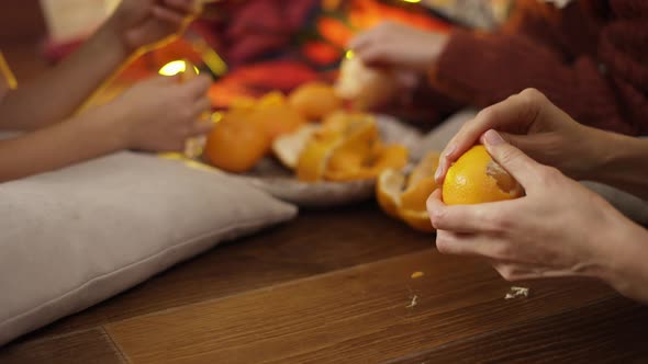 Close Up of Hands Family Eating Mandarines Under Christmas Tree in Lights