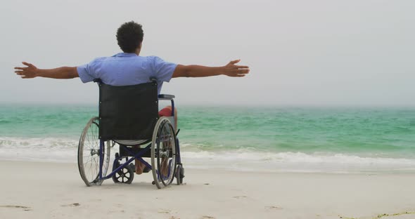 Rear view of African American man sitting with arms outstretched on wheelchair with arms outstretche