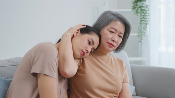Asian loving elderly mother comforts upset daughter crying for problem.