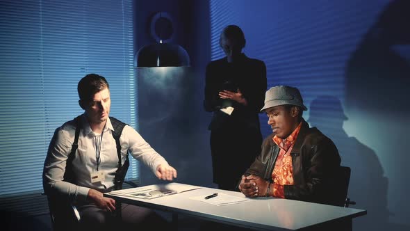 Medium Shot of Police Detective Giving Black Murder Criminal a Document To Sign a Confession About