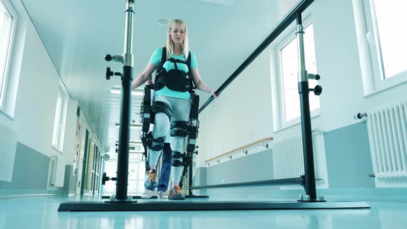 A Lady is Learning to Walk in the Exosuit with Medical Help