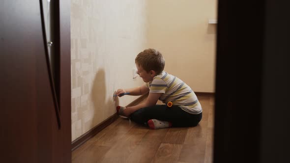 Caucasian Child Boy Sits Near Wall Draws on Wallpaper with Felttip Pen