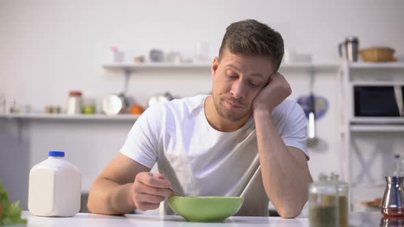 Upset Single Man Eating Tasteless Cereals for Breakfast, Lack of Appetite