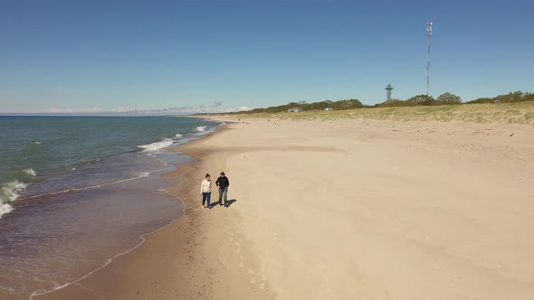 Two women are walking along the beach, view from a drone