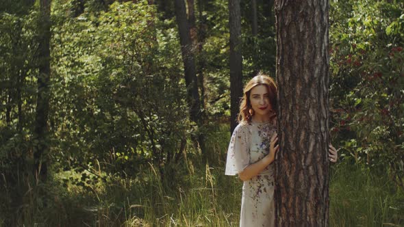 Portrait of Beautiful Young Caucasian Woman with Red Lips Posing in the Forest Near Tree Bark