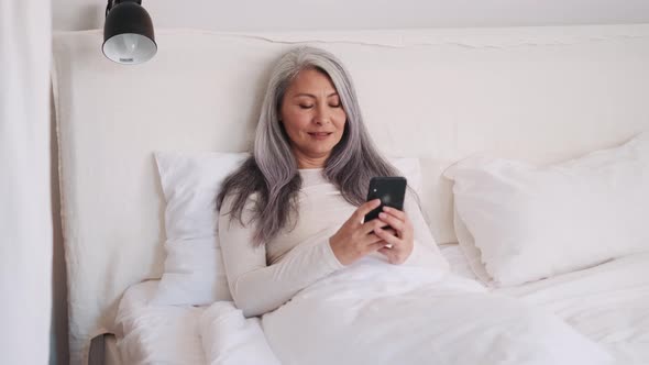 Smiling Asian woman looking at the phone