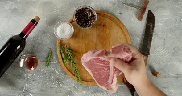 Raw Beef Steak T-bone Put on a Cutting Board Men's Hand. 