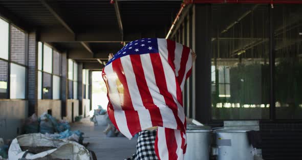 Mixed race woman holding us flag running through an empty building