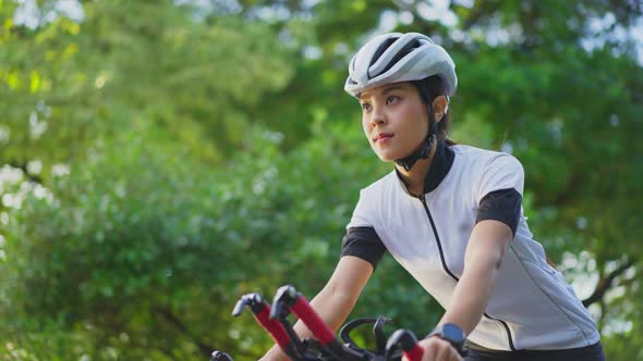 Asian young beautiful woman in sportswear riding bicycle for health in the evening in public park.