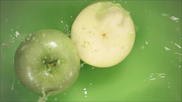 Green Apple Falling on Juice with Splash and Divided in Half
