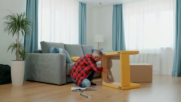 A Man Tightens a Nut Onto a Bolt with a Wrench While Assembling a Chair