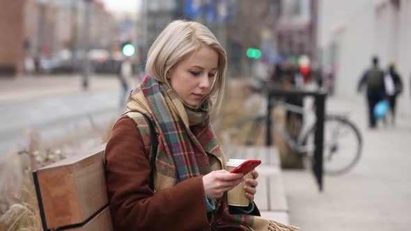 Beautiful blonde woman with cup of coffee and mobile phone