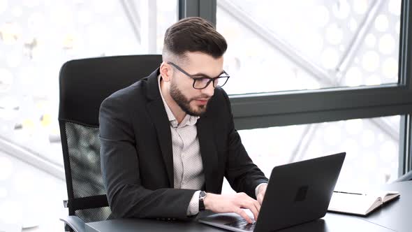 Handsome Young Man Working at Office Desk with Laptop