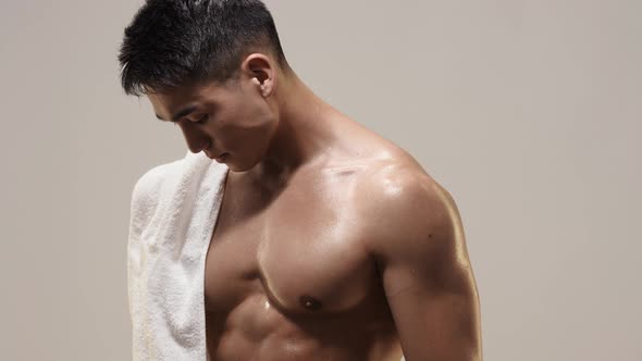 Tired Muscular Asian Man Indoors Against Gray Background