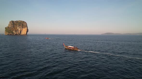 aerial drone flying parallel with two thai longtail boats during sunrise in the Andaman Sea with lar