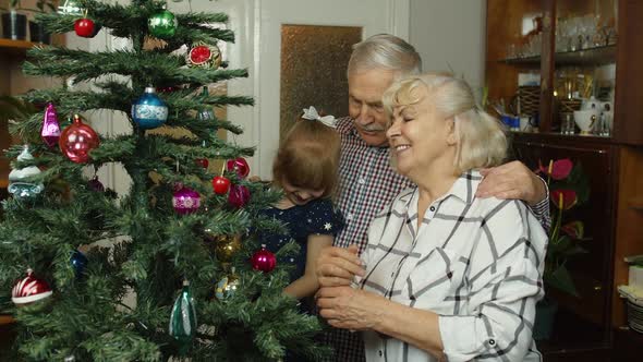 Child Girl with Senior Grandparents Family Decorating Artificial Christmas Tree New Year Holidays