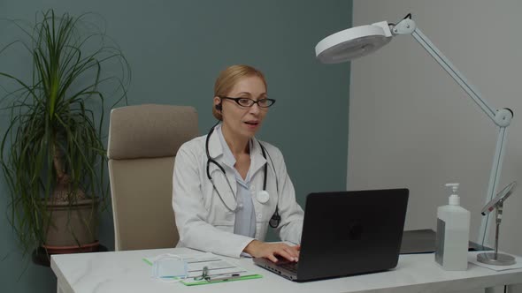Female Doctor Using Laptop Taking Part in Video Conference Indoors