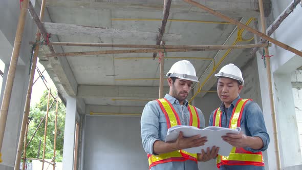 Young Asian engineers and caucasian engineer colleagues at site inspector and discuss together