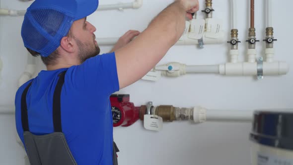 Uniformed Plumber is at Work  Closing and Opening the Taps