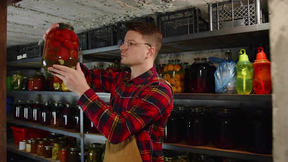 A Farmer with Glasses Checks the Quality of Pickles in the Cellar