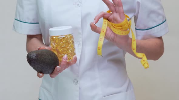 Nutritionist Doctor Holding Organic Avocado Fruit and Jar of Medicine or Vitamin or Omega 3 Capsules