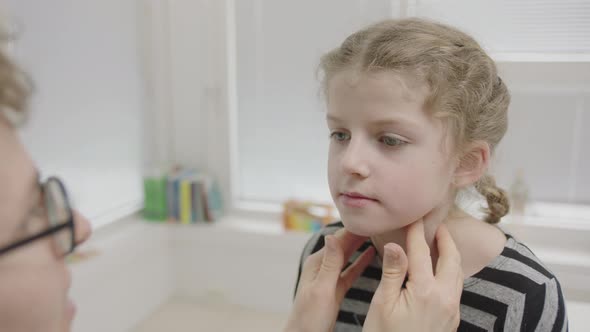 Girl Being Tested For Coronavirus By Doctor Checking Eyes, Mouth And Shoulders