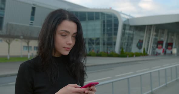 Beautiful Girl Is Smiling and Texting on the Phone When She Standing Near the Airport