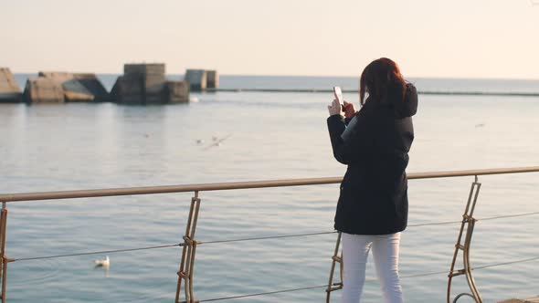 Young Beautiful Woman Walks and Enjoys the Sea on a Warm Winter Day