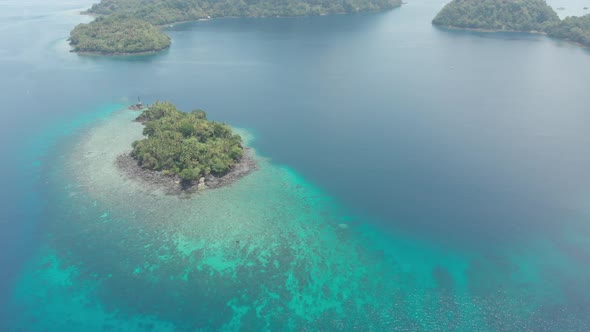 Aerial: flying over tropical island Banda Islands Maluku Indonesia turquoise water coral reef