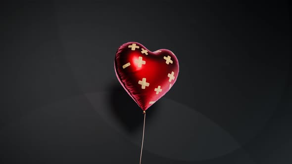 Red heart-shaped balloon fixed with bandaids. Broken heart concept. 4kHD