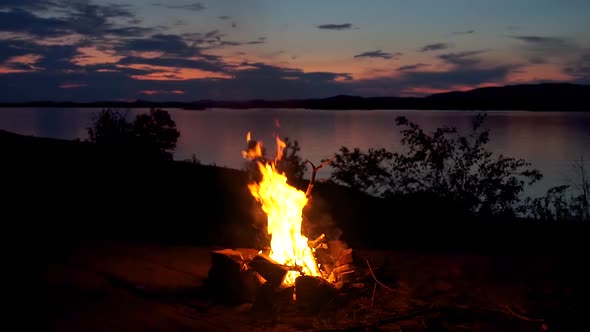 Amazing Bonfire By The Beautiful Lake In Canada On A Cold Evening With The Sunset, Mountains and Clo