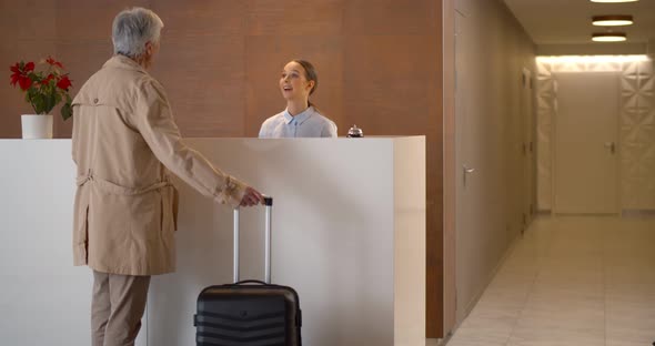 Mature Businessman with Suitcase Checking in at Hotel