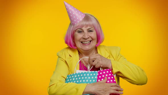 Elderly Granny Woman Showing Shopping Bags Advertising Discounts Looking Amazed with Low Prices