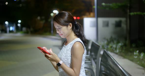 Woman check on mobile phone in city at night