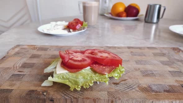 Close up healthy sandwich with tomato, sausage, cheese and salad.  Sandwich lies on сutting board