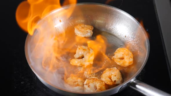 Chef Prepares Prawns with Fire in Frying Pan in Restaurant Kitchen. Slow Motion. Seafood Dish Cooked