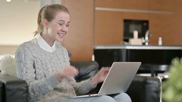 Young Woman Celebrating Success on Laptop at Home