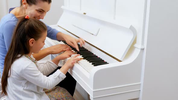 Mother assisting daughter in playing piano 4k