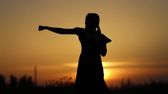 Silhouette of unrecognizable woman punching the air during sunset in outdoors, sport boxing and trai