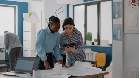 Team of Architects Working with Tablet to Analyze Blueprints Plan on Table