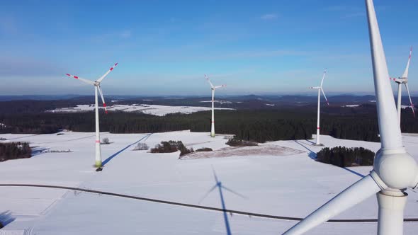 Aerial shot of a windfarm in a snowy winter landscape. Flying through a wind farm.