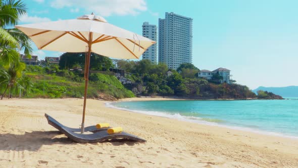 Pattaya Beach. Resort day beds and coffee table with umbrella on the beach. Sea waving with blue sky