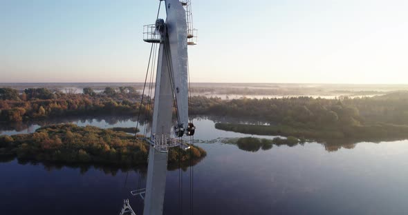 Boom of an Idle Port Crane on the Background of the River at Dawn