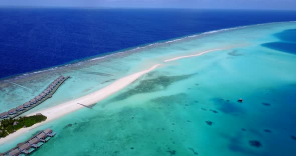 Wide flying clean view of a white sand paradise beach and blue water background in vibrant 4K