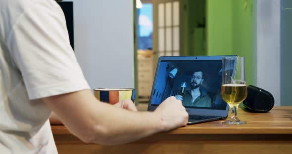 Rear View of a Man Drinking Beer and Clinking Glasses with His Friend Online Video Call While